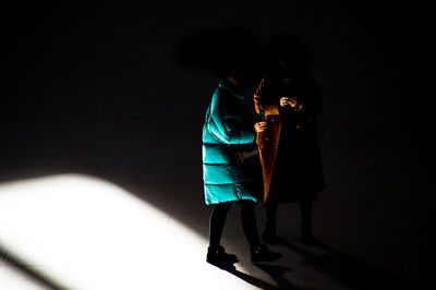 Rear view of couple standing against the dark