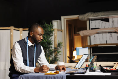 Side view of man using digital tablet while sitting at home