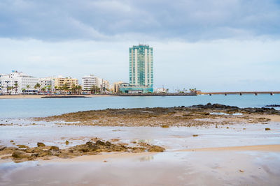 Scenic view of sea by buildings against sky