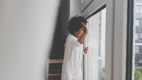 Girl standing by window at home