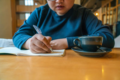 Young woman writing in book at table