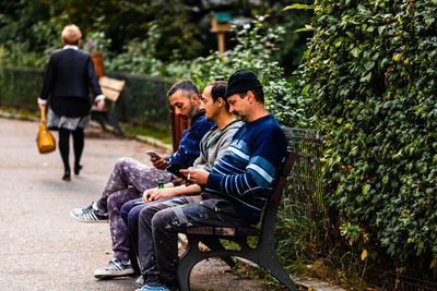 Men sitting on seat against plants