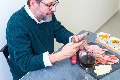 Midsection of man holding smart phone on table