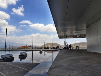 People at airport runway against sky