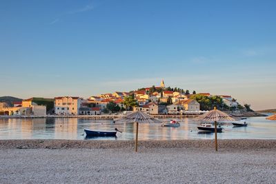 Boats moored on sea by buildings against sky in city