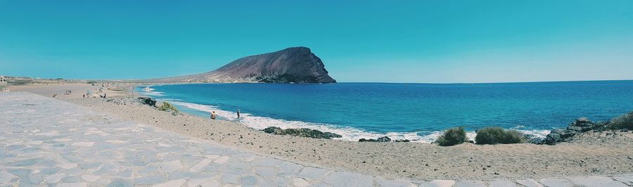 Scenic view of beach against clear blue sky