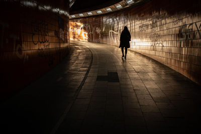 Rear view of man walking on footpath in tunnel