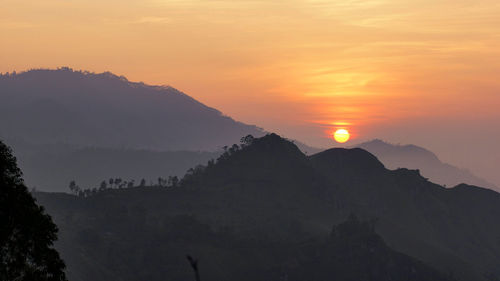 Scenic view of silhouette mountains against orange sky