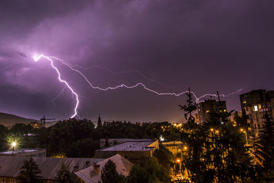 Lightning over illuminated city against sky at night