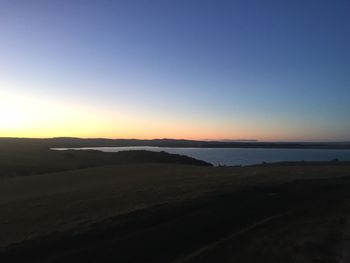 Scenic view of desert against clear sky during sunset