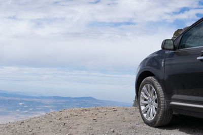 Low angle view of cropped car against cloudy sky