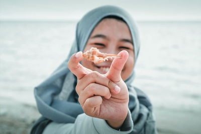 Smiling teenage girl holding seashell at beach