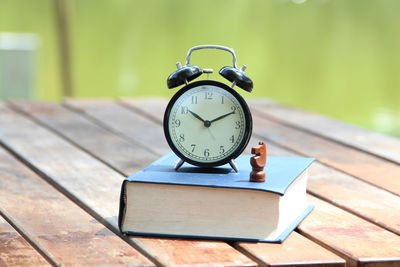 Close-up of alarm clock and chess piece on book at table