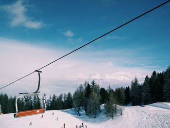 Ski lift over snow covered landscape against sky