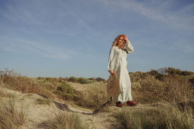 Rear view of woman standing on field against sky