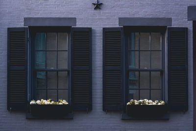 Traditional windows with black wooden shutters on a gray brick wall of an apartment building