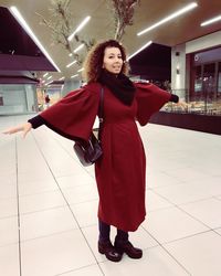 Full length portrait of young woman standing on tiled floor