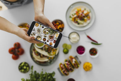 Person photographing healthy feast with various mexican foods