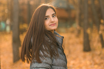 Young woman standing against trees