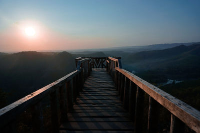 Footbridge against landscape and sky during sunset
