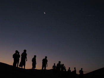 Silhouette men standing on mountain against clear sky at dusk