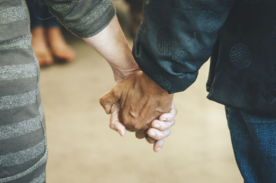 Midsection of couple holding hands