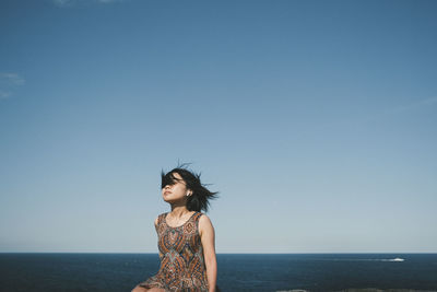 Young woman standing against sea