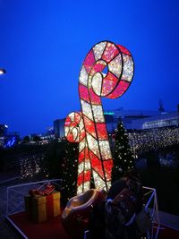 Illuminated ferris wheel against blue sky at night