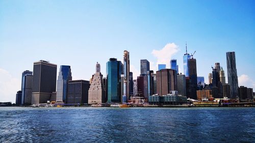 Modern buildings by river against sky in city