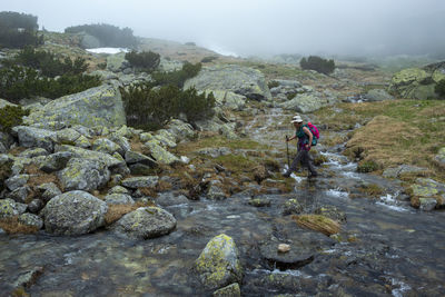 People walking on rocks by mountain