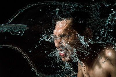 Close-up of shirtless man in water against black background