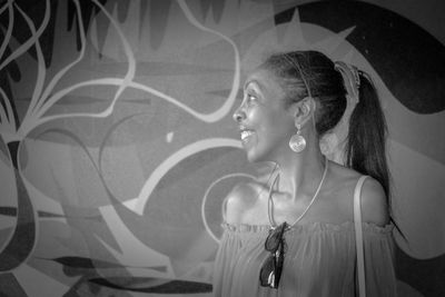 Side view of young woman looking away against wall