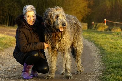 Portrait of woman with dog on footpath during sunset