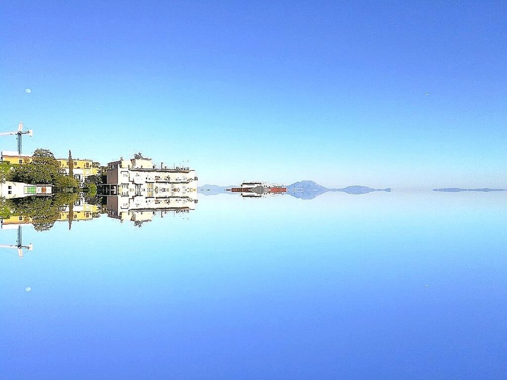 REFLECTION OF BUILT STRUCTURE AGAINST CLEAR BLUE SKY