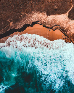 Detail shot of sea waves and sand beach shore with a cave from puerto rico