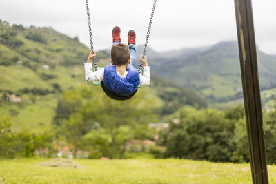 Rear view of boy swinging in playground