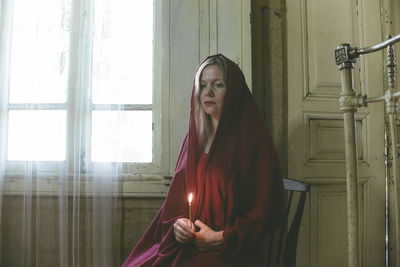 Woman holding candle while sitting at home