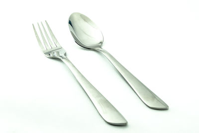 Close-up of fork and spoon over white background
