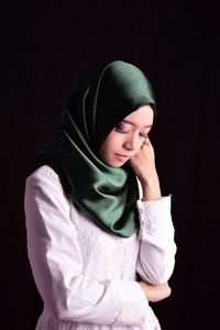 Young woman in hijab against black background