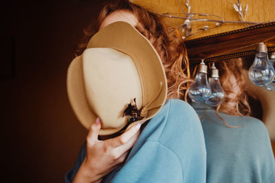 Woman covering face with hat while sitting at home