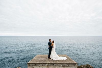 Couple standing by sea against sky