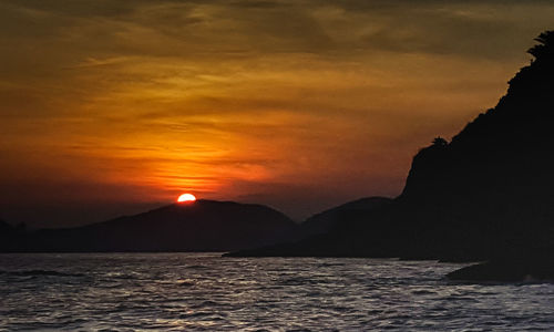 Scenic view of sea against dramatic sky during sunset