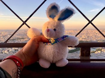 Cropped hand holding stuffed toy against cityscape