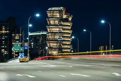 Light trails on road against illuminated city at night