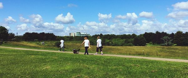 Rear view of men playing soccer on field against sky