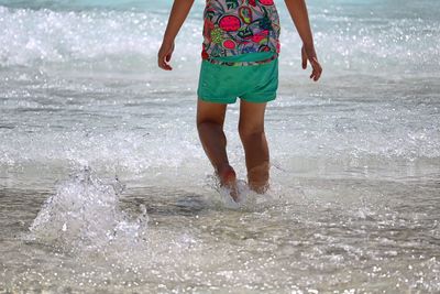 Low section of child wading in sea