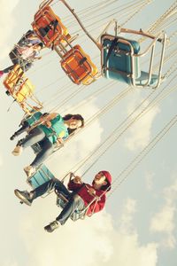 People on chain swing ride against sky