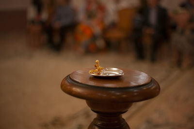 Wedding rings lie in golden saucer. stand made of wood at wedding ceremony.
