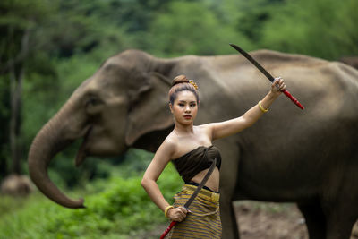 Portrait of girl holding sword in front of elephant