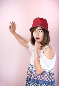 Shocked young woman standing against pink background